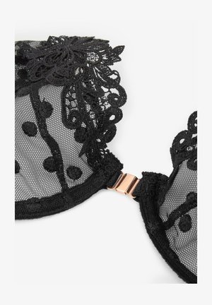 Czarna koronkowa biustonosz z przezroczystym siateczkowym wzorem, zdobiony kropkami, haftem kwiatowym oraz z różowo-złotym metalowym zapięciem z tyłu.