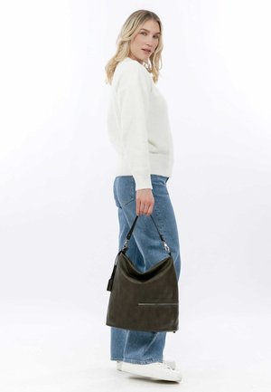 Dark green leather hobo bag with a slouchy design, zippered pocket, and a detachable strap. Model wears white sweater and light blue jeans.