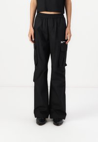 Μαύρο cargo παντελόνι με ελαστική μέση, πλαϊνές τσέπες και φαρδιά γραμμή. Φτιαγμένο από λείο ύφασμα με διακριτική λεπτομέρεια λογότυπου.