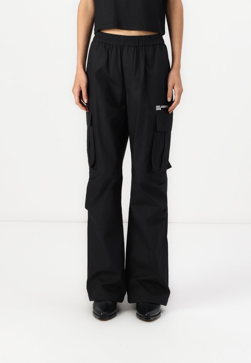 Μαύρο cargo παντελόνι με ελαστική μέση, πλαϊνές τσέπες και φαρδιά γραμμή. Φτιαγμένο από λείο ύφασμα με διακριτική λεπτομέρεια λογότυπου.
