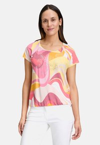 T-shirt z krótkim rękawem, okrągłym dekoltem, wykonany z miękkiego materiału w pastelowych kolorach, z falistymi wzorami i akcentami z dżetów z przodu.