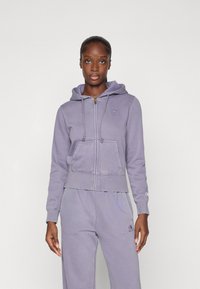 Cropped purple zip-up hoodie made of cotton blend, featuring a hood, drawstring, front pockets, and a small logo on the chest.