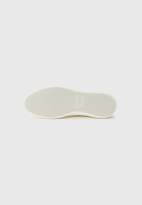 Cream rubber shoe sole with a textured zigzag pattern. Features a rectangular logo imprint near the center. Smooth surface, rounded shape.