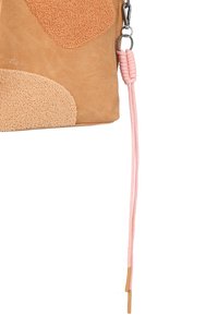 Bolso de color melocotón y texturizado, con acentos de tela, que presenta una correa trenzada rosa y hardware plateado. Forma rectangular con un acabado suave.