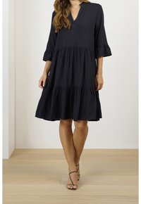 Navyblaues, knielanges Kleid mit V-Ausschnitt und gerafften Dreiviertelärmeln. Verfügt über ein gestuftes Design und eine glatte Stofftextur.