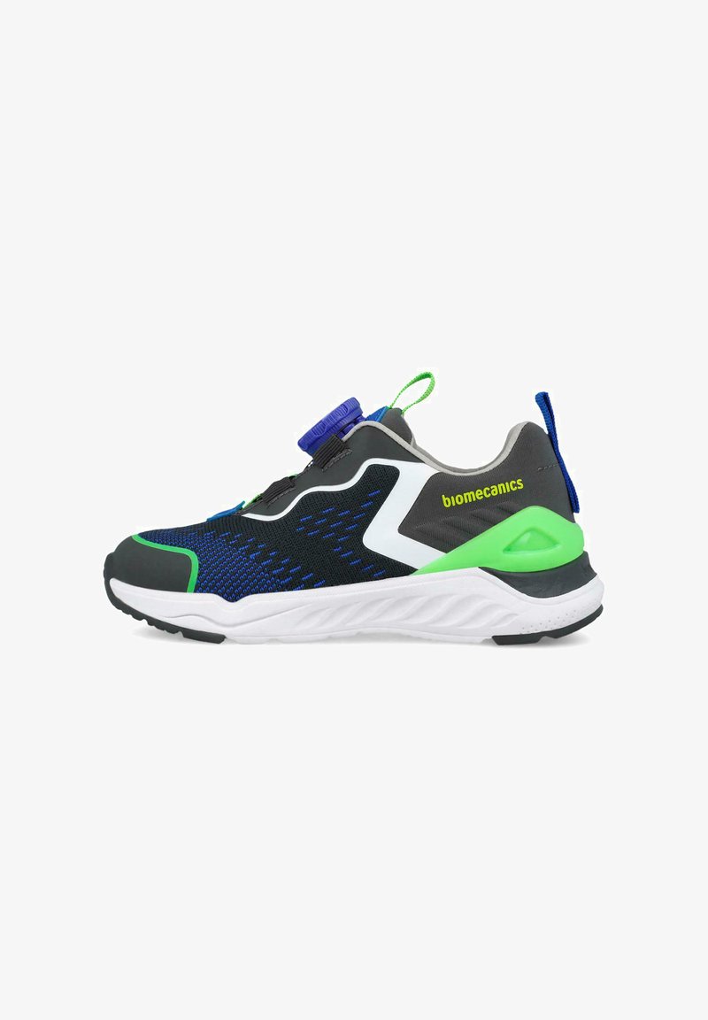 Zapatilla deportiva infantil con parte superior de malla negra, azul y verde, acentos blancos y suela de goma. Cuenta con un sujetador circular azul en la lengüeta.