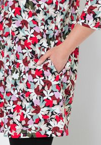Bloemenprint jurk met een mix van rode, witte en groene bladeren op een zwarte achtergrond. Inclusief zijzakdetail en korte mouwen.