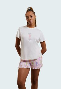 Vit bomullströja med sjöhästgrafik, matchad med pastellfärgade shorts med horisontell randig mönster och volangkant.