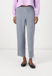 Pantaloni de trening gri deschis, cu croială lejeră și talie elastică, fabricați din țesătură moale; au cusături laterale și picioare drepte.