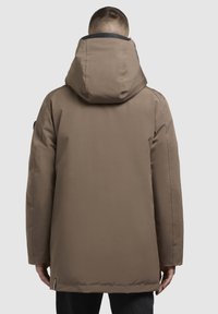 Chaqueta acolchada marrón con capucha, que presenta una textura suave, mangas largas y un ajuste ligeramente entallado en la cintura.