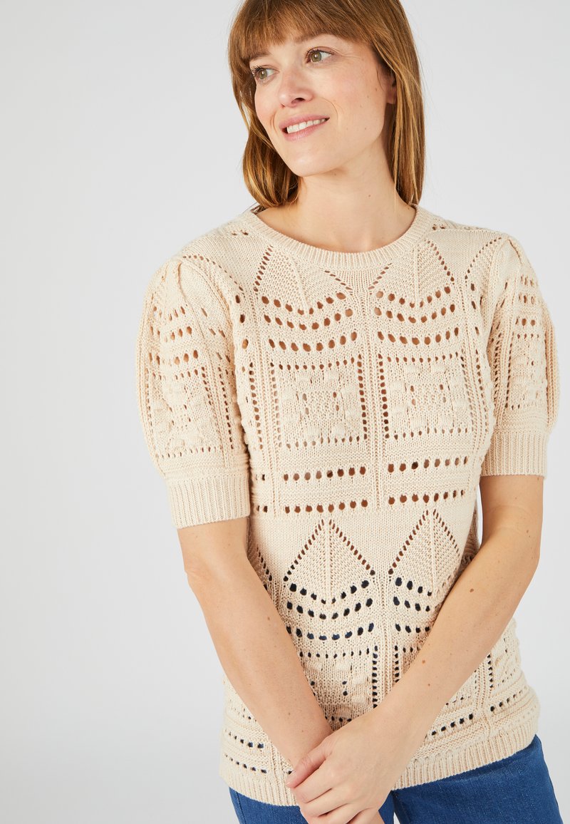 Crèmekleurige gebreide sweater met korte mouwen, voorzien van een openwerk patroon met geometrische ontwerpen en textuurelementen. Rib gebreide zoom en manchetten.