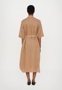 Tan lin midikjole med korte ermer, belte i livet og rett silhuett. Minimalistisk design, glatt tekstur.