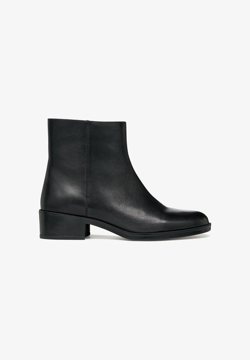 Bota de cuero negro hasta el tobillo con puntera redondeada, tacón bajo y cuadrado, y un sutil detalle de costura a lo largo de la suela. Textura suave, diseño minimalista.