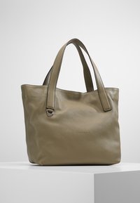 Torba na ramię z oliwkowej skóry, z dwoma paskami na ramię, gładką fakturą i minimalną ilością okucia. Na przodzie znajduje się subtelne logo.