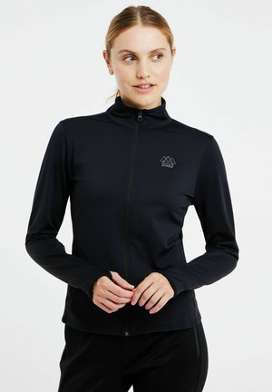Musta vetoketjullinen takki istuvassa muotoilussa, jossa on korkea kaulus, pitkät hihat ja pieni vuoristologot t-paidan rinnassa. Sujuva pinta.
