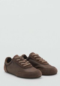 Sneaker in suede marrone con dettagli in pelle liscia, punta arrotondata e lacci a contrasto. Design a profilo basso, texture morbida e stile minimalista.