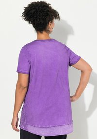 Paarse T-shirt met korte mouwen en een gradient ontwerp. Heeft een ronde halslijn, een losse pasvorm en zijsplitten bij de zoom.