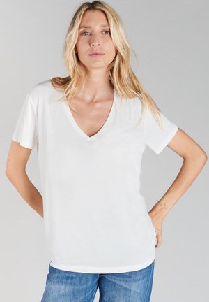 Witte v-hals t-shirt gemaakt van zachte stof met korte mouwen. De pasvorm is ontspannen en heeft subtiele naaddetails en een gebogen zoom.
