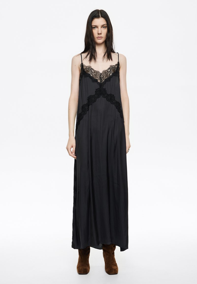 Mustmust satiinmaxi kleit pitsakestega, hõbesetõhvuga ja vooluva siluettiga, kombineeritud pruuni suede pahkluuketega saapaga.