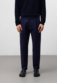 Marineblauwe broeken met een gladde textuur, rechte voorkant en geplooid ontwerp. Gekocht met een donkergroen langemouwenshirt en zwarte schoenen.