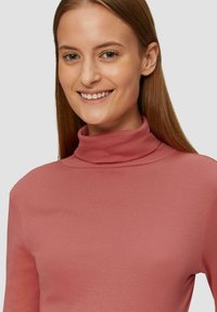 Langsleeve, ribbel turtleneck top in stofkleur, met een aansluitend ontwerp en een gladde textuur. Geen opmerkelijke patronen of accenten aanwezig.