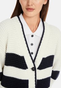 Chunky Strickjacke in Creme und Marineblau gestreift, mit einem Schalkragen, strukturiertem Stoff und einer großen Knopfleiste.