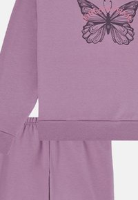 Lavendelfarbenes Sweatshirt und passende Hose. Das Sweatshirt hat ein schwarzes Schmetterlingsmuster mit rosa Akzenten; weicher Stoff, elastischer Bund.
