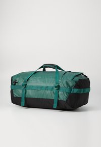 Green and black duffel bag featuring a rectangular shape, sturdy straps, and a zippered closure with side handles and accents.