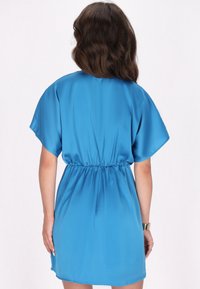 Rochie din satin albastru cu mâneci scurte, talie elastică și croială lejeră. Textură netedă și lungime deasupra genunchiului, cu un design minimalistic.