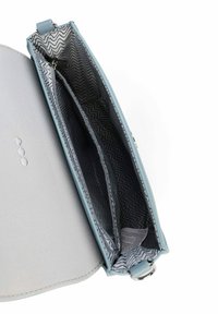 Světle modrá kabelka s hladkým povrchem a vzorovaným vnitřkem s cikcak liniemi. Má dvě přihrádky a zapínání na zip.