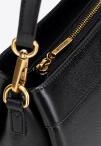 Czarna skórzana torebka o teksturowanej powierzchni, ze złotymi akcentami i zamknięciem na zamek z logo na uchwycie. W zestawie regulowany pasek.