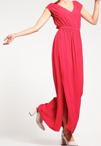 Robe longue rose avec des manches courtes, taille cintrée et décolleté en V. Présente une silhouette fluide et des fentes sur les côtés pour une liberté de mouvement.