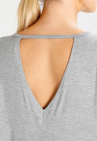 Graues T-Shirt mit V-Ausschnitt hinten, aus weichem Stoff mit glatter Textur, das minimalistische Designdetails hervorhebt.