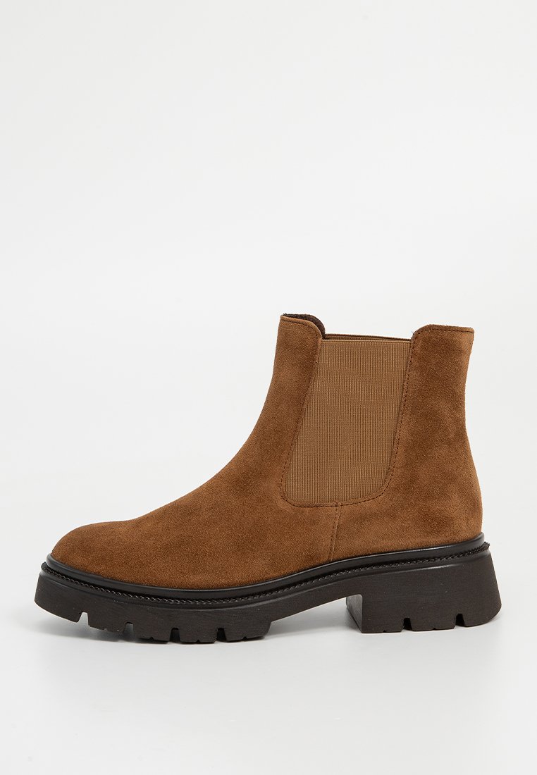 Braune Wildleder-Sneakers mit elastischen Seiteneinsätzen, runder Zehenpartie und einer klobigen schwarzen Gummisohle. Texturierte Oberfläche und strapazierfähige Verarbeitung.