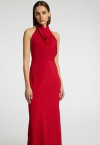 Abito rosso con collo halter, scollatura drappeggiata, silhouette aderente e tessuto testurizzato, che arriva fino al pavimento. Design liscio e privo di decorazioni.