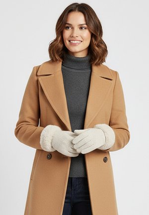 Tan wool blend coat with a notched collar, grey ribbed turtleneck, and cream gloves featuring soft, textured cuffs.