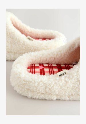 Biele, nadýchané papuče na zasunutie s mäkkým, textúrovaným povrchom. Vnútorná výstelka s červeným károvaným vzorom a malá štítok s nápisom „NEXT“ na boku.