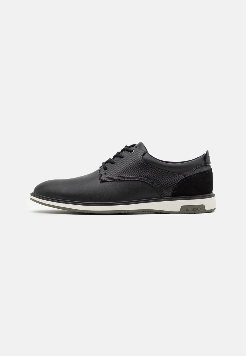 Chaussure noire à lacets pour homme, basse, avec panneaux latéraux texturés, semelle blanche et détail de marque gris sur le talon.