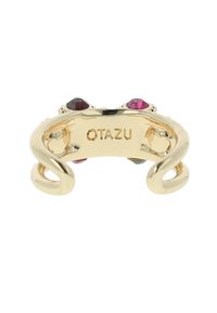 Gouden metalen ring met een spiraalontwerp, voorzien van twee gekleurde stenen, gemarkeerd met "OTAZU" op de binnenband. Glad oppervlak, glanzende afwerking.