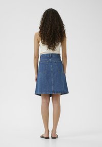 Jeans-A-Linien-Rock in Mittelblau mit hoher Taille, zwei Gesäßtaschen und einem Saum, der über den Knien endet. Glatte Textur.
