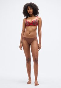 Soutien-gorge rouge à imprimé léopard avec armatures et bretelles réglables, associé à un slip bikini marron, doté d'une coupe taille basse.