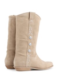 Bottes hautes en suède beige avec des boutons en forme d'étoile argentés et des accents en strass sur le côté. Talon en bois plat. Texture lisse.