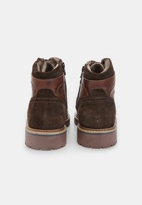 Stivali ankle in suede e pelle marroni con finitura texturizzata, dotati di una chiusura laterale con zip e una suola robusta marrone per una migliore aderenza.