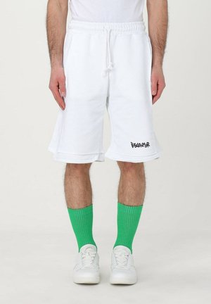 Pantaloni corti in cotone bianco con vita elastica e cordoncino, con logo nero sull'orlo. Abbinati a calze a coste verdi.