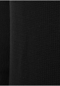 Musta neulottu kangas, jossa on teksturoitu, röyhelöinen kuvio. Materiaali näyttää pehmeältä, tiheältä ja väri on tasainen.