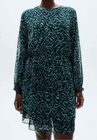 Vestido verde con estampado hecho de tela ligera, que presenta mangas largas y transparentes, además de una cintura ajustada. El dobladillo tiene un detalle de ribete de puntos.