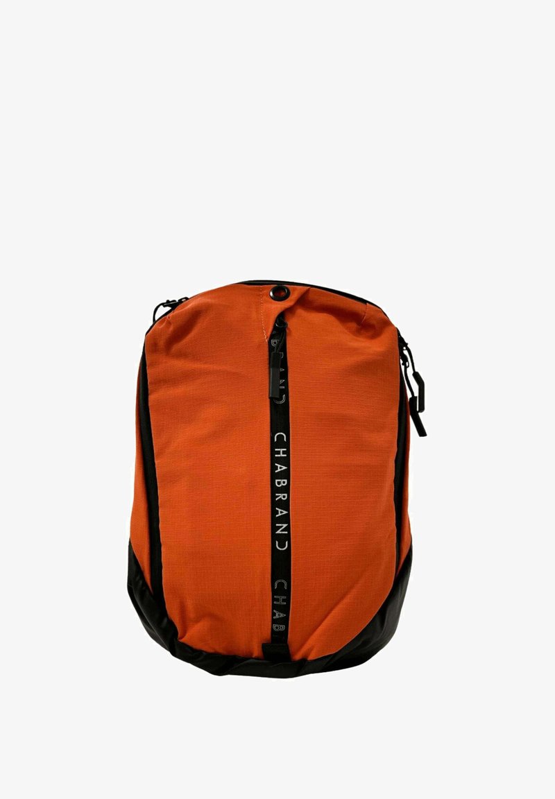 Sac à dos orange avec un fond noir, fermeture éclair et sangle avec logo sur le devant. Fait de tissu texturé avec une forme arrondie et des poignées latérales.