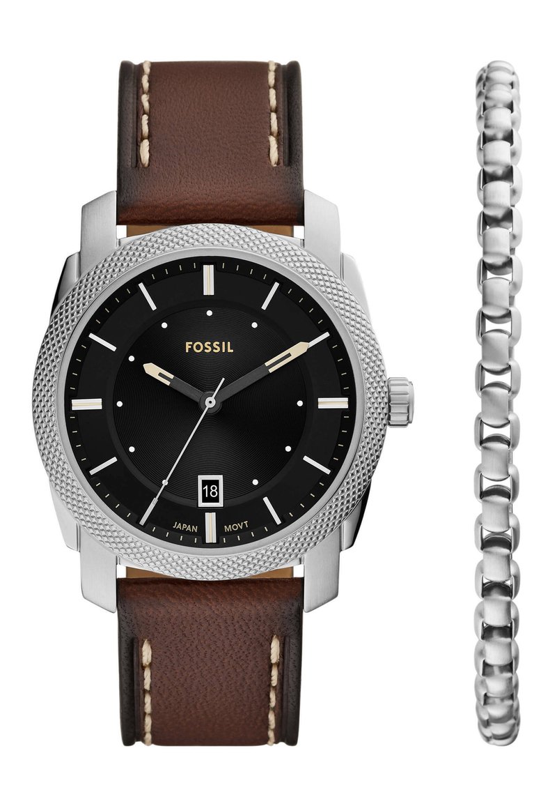 Reloj Fossil con esfera circular negra, caja plateada, correa de cuero marrón con costuras beige y un brazalete plateado a un lado.