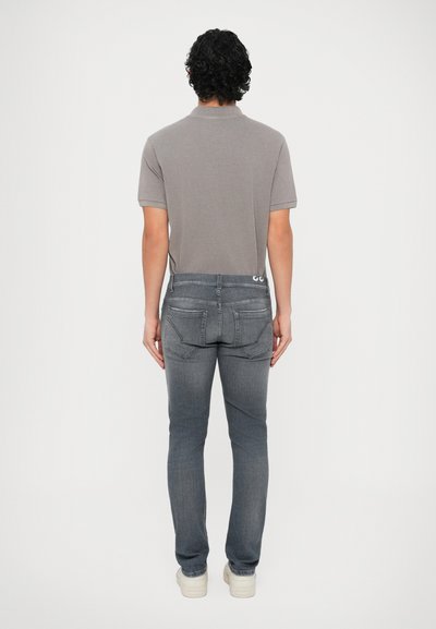 Γκρι πόλο μπλούζα με γιακά, συνδυασμένη με σκούρο γκρι τζιν με ζώνη δύο κουμπιών και λευκά ραφές. Συνδυάζεται με λευκά αθλητικά παπούτσια.