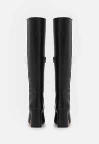 Black leather knee-high boots with a square heel, featuring a zipper detail on the side and a smooth texture.